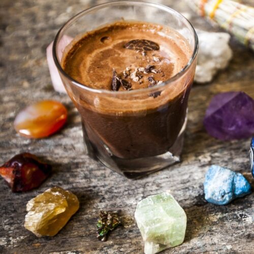 A delicious hot chocolate served in a glass cup circled by stone gems in different colors