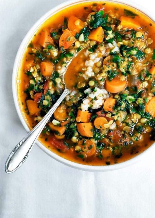 A delicious colorful vegan casserol with carrots, greens and wheat in a tomato sauce